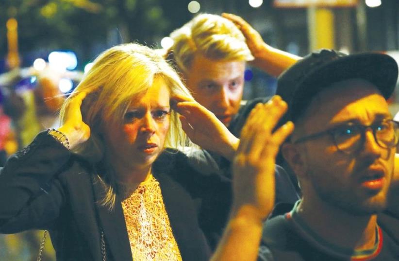 PEOPLE LEAVE the area of Saturday night’s terrorist attack near London Bridge with their arms raised to indicate they are not a danger. (photo credit: REUTERS)