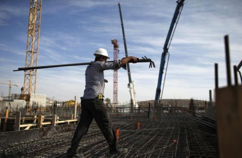 A laborer works on an apartment building under construction in the Har Homa neighborhood of Jerusalem (photo credit: REUTERS)