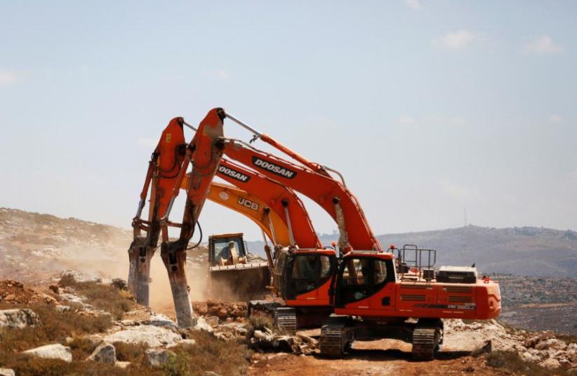 Heavy machinery work on a field as they begin construction work of Amichai, a new settlement which will house some 300 Jewish settlers evicted in February from the settlement of Amona, in the West Bank June 20, 2017. (photo credit: REUTERS/Ronen Zvulun)