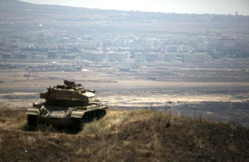 The Syrian area of Quneitra is seen in the background as an out-of-commission Israeli tank parks on a hill, near the ceasefire line between Israel and Syria, in the Golan Heights. (photo credit: BAZ RATNER/REUTERS)