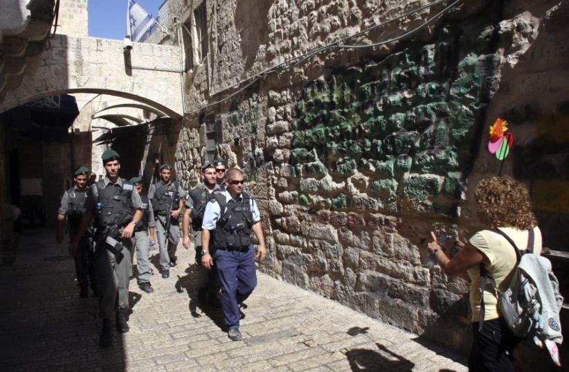 A tour guide (R) walks near Israeli police and border police officers in Jerusalem's Old City. (photo credit: REUTERS/Ronen Zvulun)