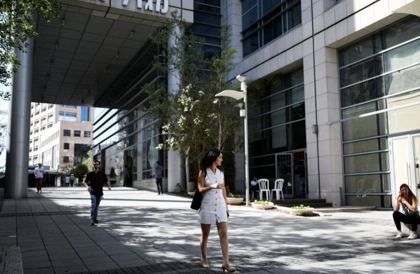 A woman walks near high-rise buildings in the hi-tech business area of Tel Aviv (photo credit: REUTERS/AMIR COHEN)