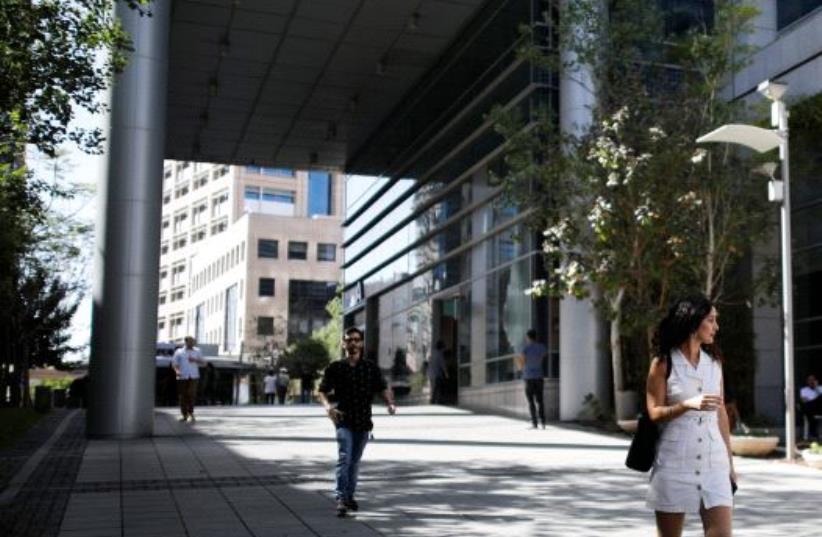 A woman walks near high-rise buildings in the hi-tech business area of Tel Aviv (photo credit: REUTERS/AMIR COHEN)