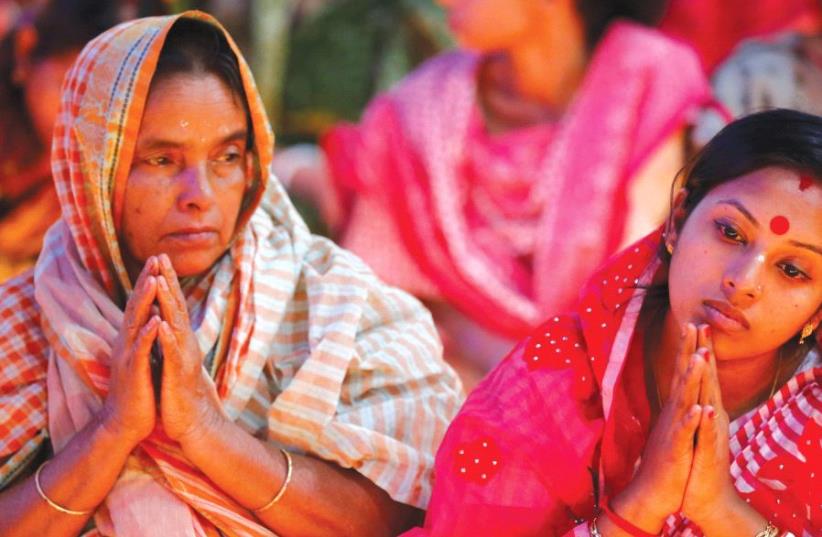 HINDU DEVOTEES sit together on the floor of a temple to observe Rakher Upabash for the last day, in Dhaka, B (photo credit: REUTERS)