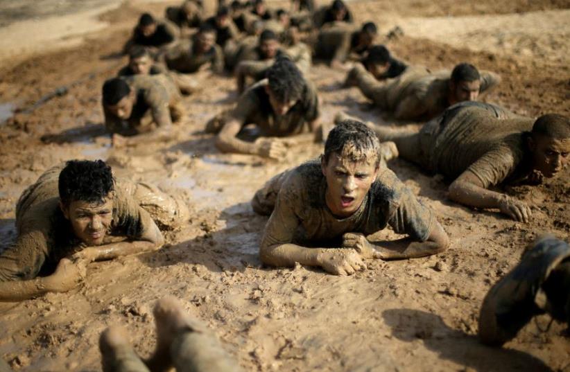 Young Palestinians crawl during a military-style exercise at a Hamas summer camp in Rafah in the southern Gaza Strip July 27, 2017. (photo credit: REUTERS)