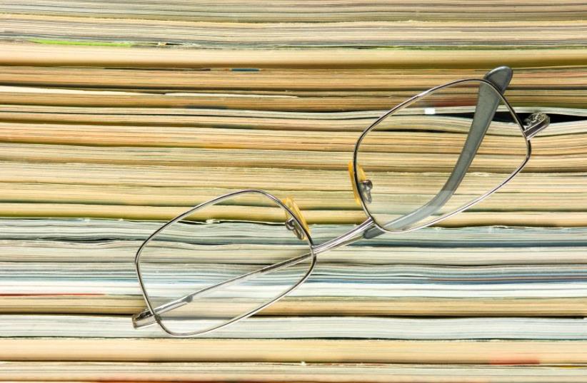 glasses on the background of the stack of magazines (photo credit: INGIMAGE)