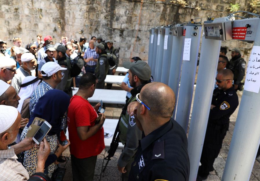  Palestinians stand in front of Israeli police officers and newly installed metal detectors at an entrance to the Temple Mount, in Jerusalem's Old City July 16, 2017. (REUTERS)