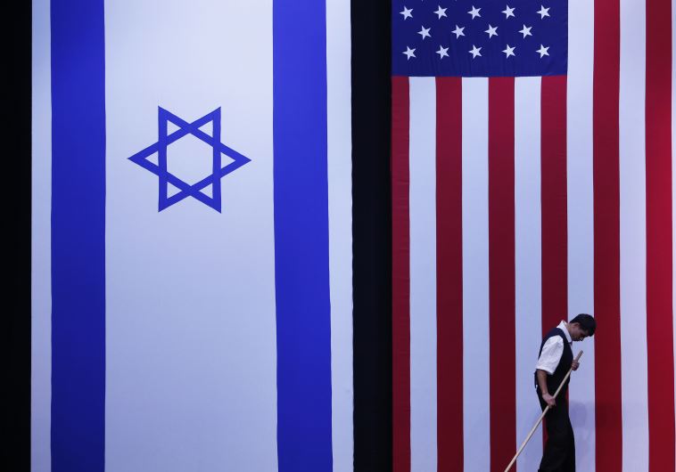 A worker cleans the stage near Israeli and American flags  (credit: REUTERS)