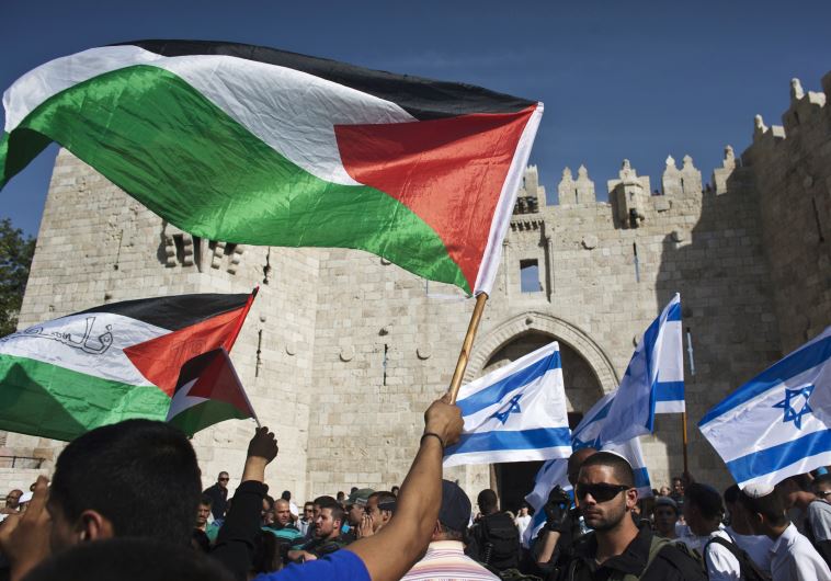 Palestinian protesters wave Palestinian flags as Israelis carrying Israeli flags walk past in front of the Damascus Gate outside Jerusalem's Old City (credit: REUTERS)