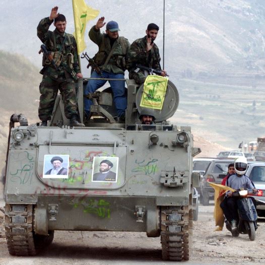 Pro-Iranian Hezbollah guerrillas, riding on an APC M113 used by pro-Israeli militiamen, wave to passing motorists as they drive in the former Israeli security zone in the Tell Nahas area of south Lebanon May 26, 2000.  (credit: REUTERS)