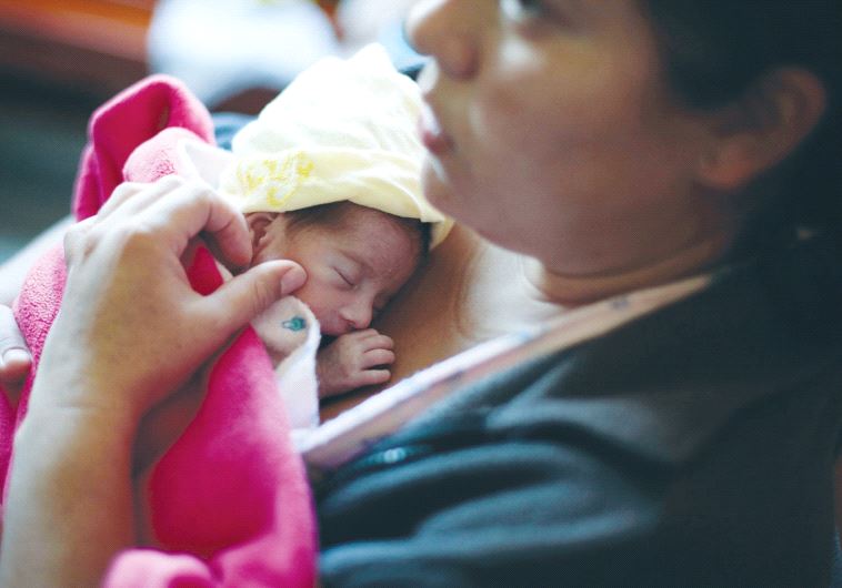 A MOTHER hugs her baby soon after giving birth. (credit: REUTERS)