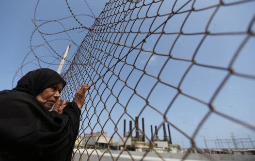 A Palestinian woman stands by a fence during a protest calling for an end to the power crisis, outside the power plant in the central Gaza Strip April 23, 2017. (credit: REUTERS)