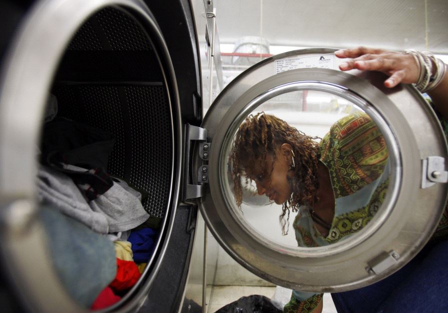 A woman loads laundry into the washing machine at a laundromat in Cambridge, Massachusetts July 8, 2009. (credit: REUTERS/BRIAN SNYDER)