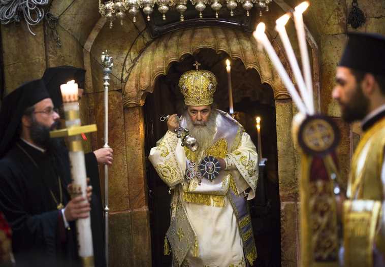 Greek Orthodox Patriarch of Jerusalem Metropolitan Theophilos (C) takes part in the Easter Sunday mass procession inside the Church of the Holy Sepulchre in Jerusalem's old city