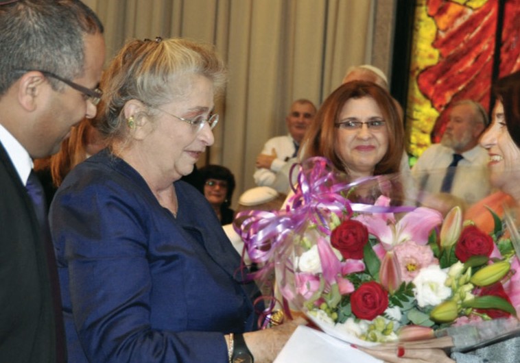 Nechama Rivlin (center) accepts a bouquet from author Dina Kit