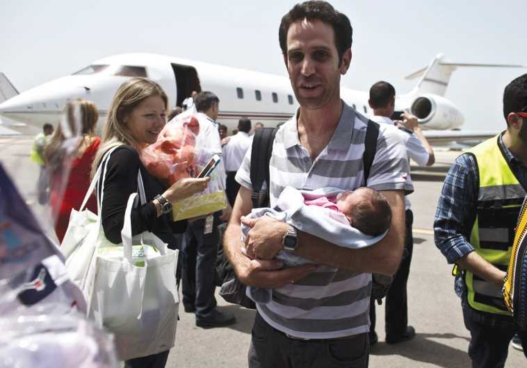 A man holds his baby, born to a surrogate mother, after being evacuated from Nepal and landing at Sde Dov Airport in Tel Aviv