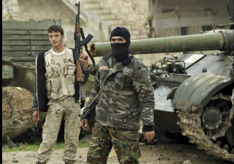 Ahrar al-Sham Islamic rebel fighters stand beside tanks left behind by forces loyal to Syrian President Bashar Assad, in Idlib.