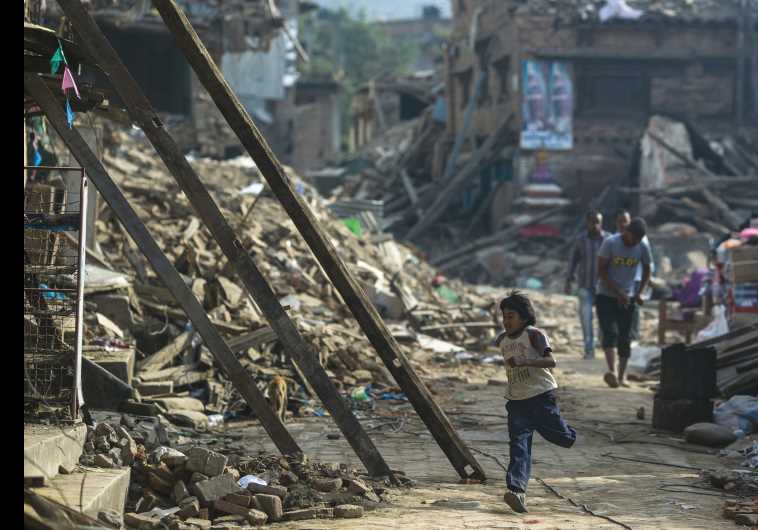 An earthquake survivor runs past collapsed houses on the outskirts of Kathmandu, May 5.