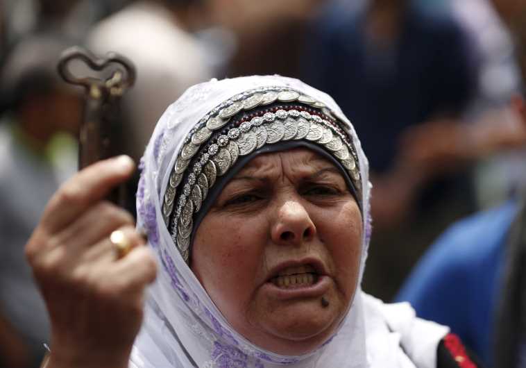 A woman holds a symbolic key as she takes part in a rally ahead of "Nakba Day" in Ramallah on May 13, 2015