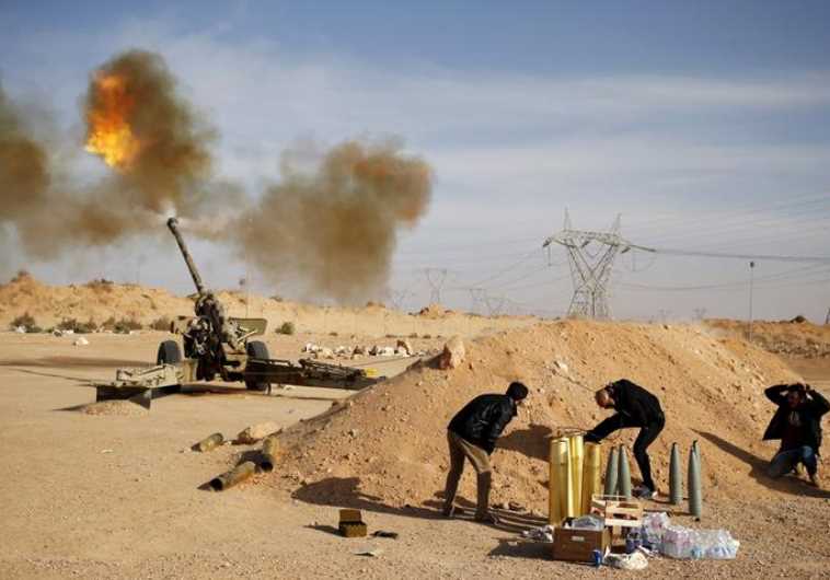 Libya Dawn fighters fire an artillery cannon at IS militants near Sirte.