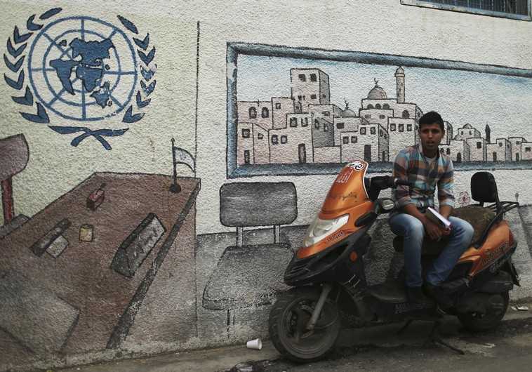 A Palestinian student sits on a motorcycle as he watches a protest at the gate of the headquarters of UNRWA in Gaza City