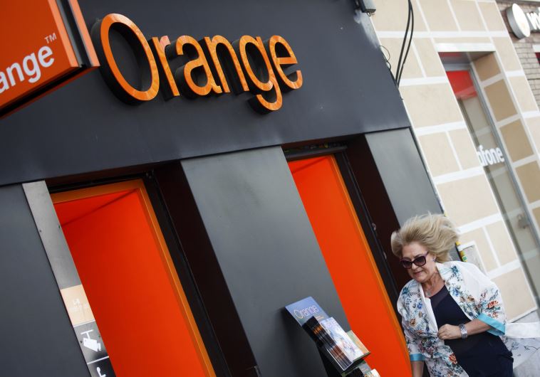 A woman walks past an Orange shop