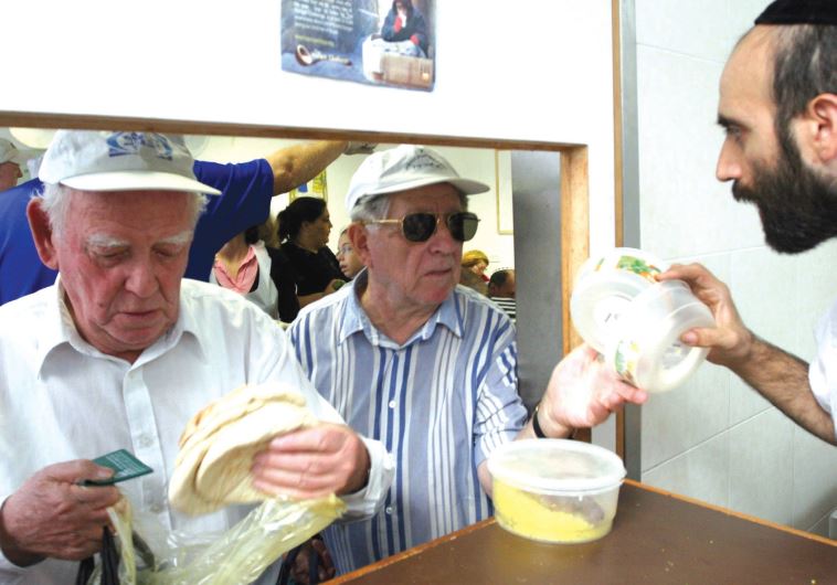 A volunteer distributes food at a soup kitchen.