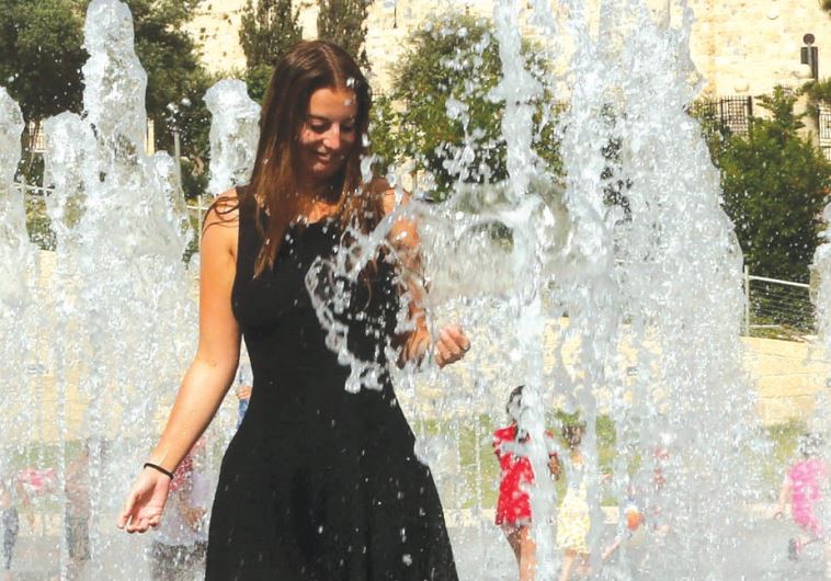 A woman plays in a water fountain in Jerusalem