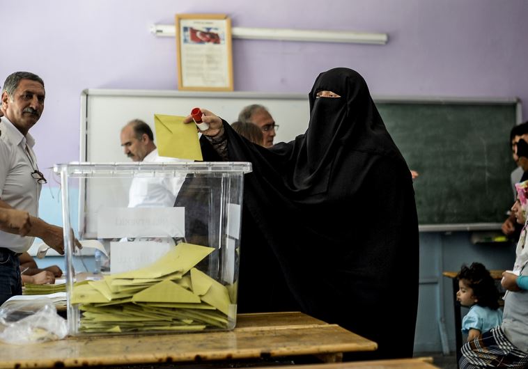 A woman casts her vote as others wait on June 7, 2015, in the southeastern city of Diyarbakir