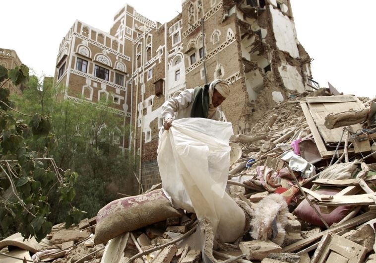 A worker searches through the rubble after Saudi-led strikes targeted the old city of Sanaa, Yemen