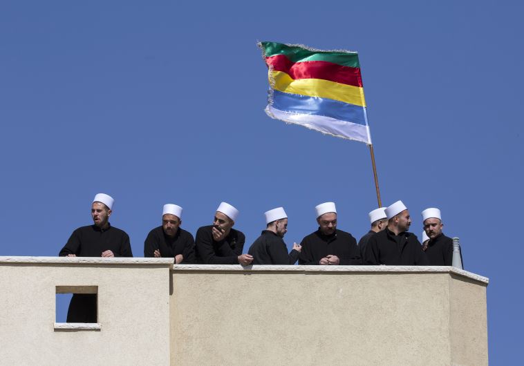 Members of the Druze community stand near a Druze flag during a rally in the Druze village of Majdal Shams.