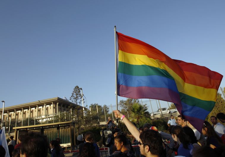 An activist waves an LGBT flag near Israel's Knesset building