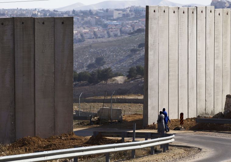 Palestinians walk near an opening in Israel's security fence in the east Jerusalem neighborhood of A-tur