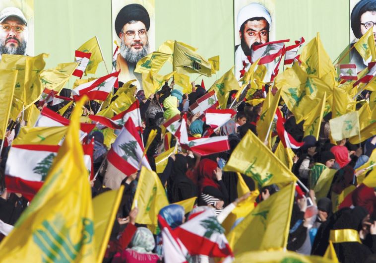 LOCALS IN NABATIYA, south Lebanon, carry Hezbollah and Lebanese flags on May 24 while the group’s leader Hassan Nasrallah speaks on a screen at a festival to commemorate the 15th anniversary of the IDF’s withdrawal from Lebanon