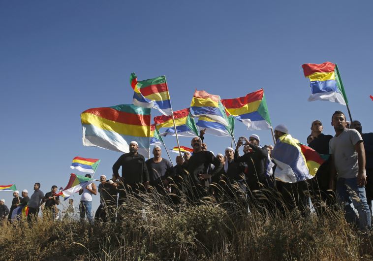 Members of the Druse community watch the fighting in the Druse village of Khadr in Syria as they stand on the Israeli side of the border fence between Syria and the Golan Heights