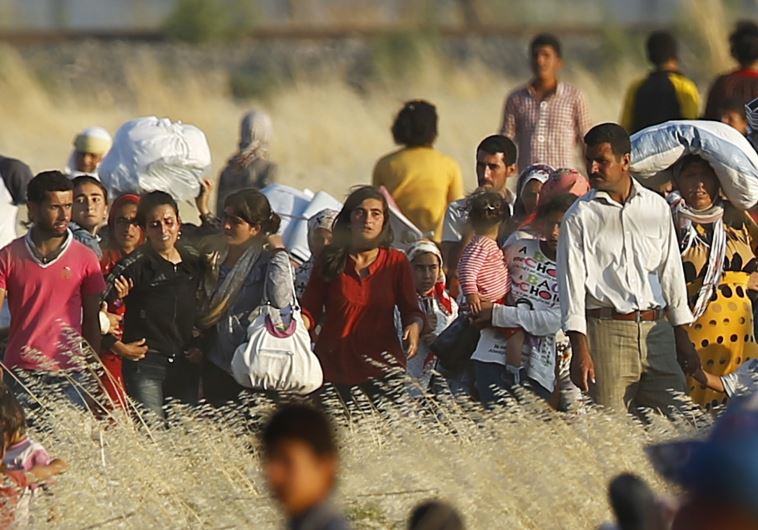 Syrian Kurds from Kobani walk to the border fences as seen from the Turkish border town of Suruc