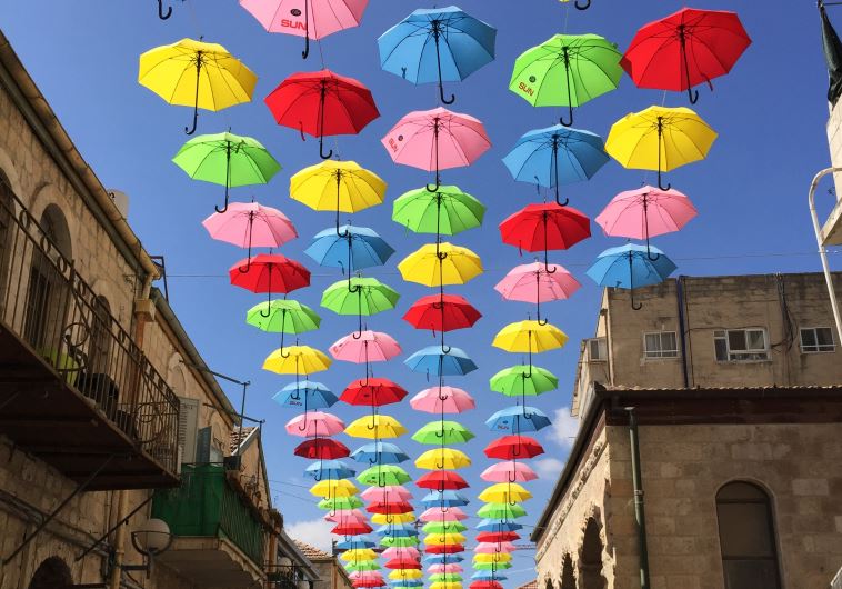 People walk under colourful umbrellas decorating a pedestrian mall in downtown Jerusalem June 30, 2015.