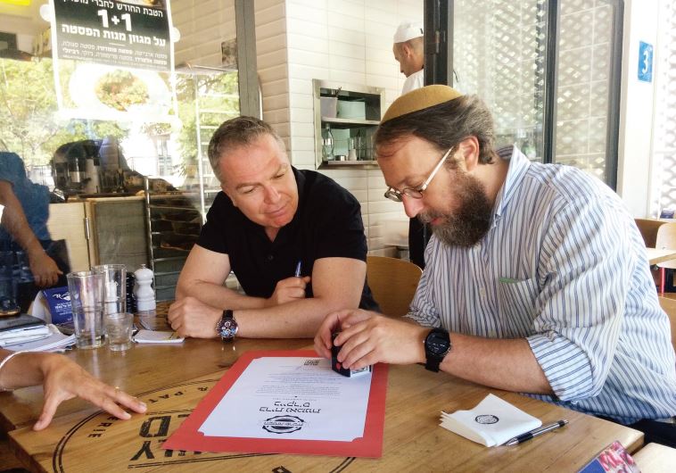 Rabbi Aaron Leibowitz and Baker’s Boulangerie and Patisserie owner Lior Glickman sign the ‘trust alliance’ certification.