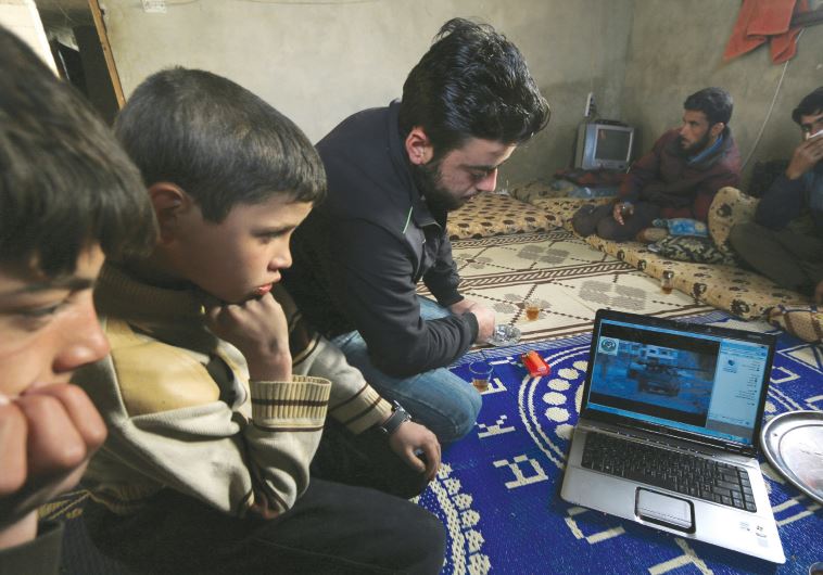 A boy in Syria watches a video on a laptop.