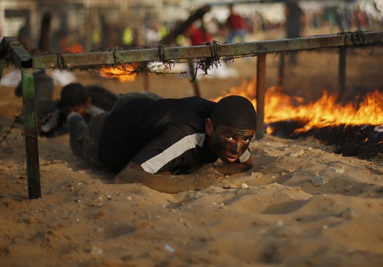 A young Palestinian crawls under an obstacle during a military-style graduation ceremony at a summer camp in Gaza