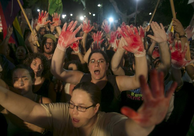 Protesters hold up gloves covered in red during a protest against the violence towards the gay community in Tel Aviv August 1, 2015