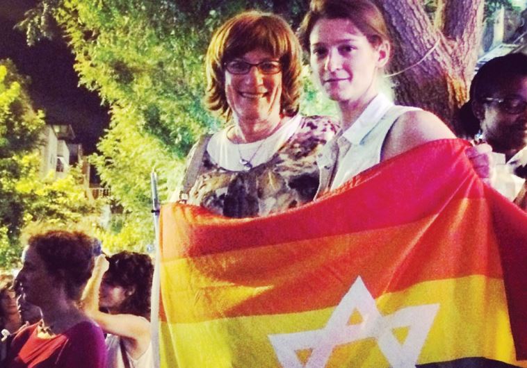 SARAH WEIL (right) and Jewish educator and trans-activist Yiscah Smith wrap themselves in a flag at the rally in Jerusalem Saturday night