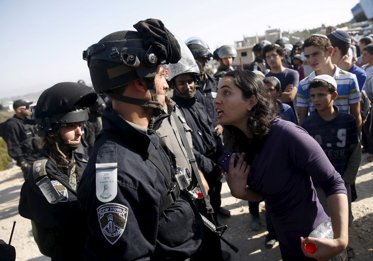 A young Jewish settler (R) speaks with an Israeli police officer near buildings slated for demolition in the West Bank Jewish settlement of Beit El