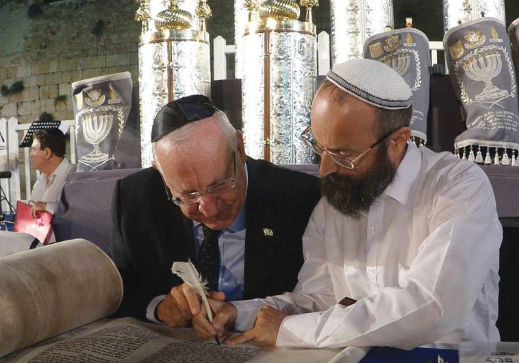 PRESIDENT REUVEN RIVLIN, with the assistance of a scribe, completes a ELIE ESTRIN (Courtesy Chabad) letter in one of the Torah scrolls dedicated at the Western Wall this week in memory of fallen soldiers. 
