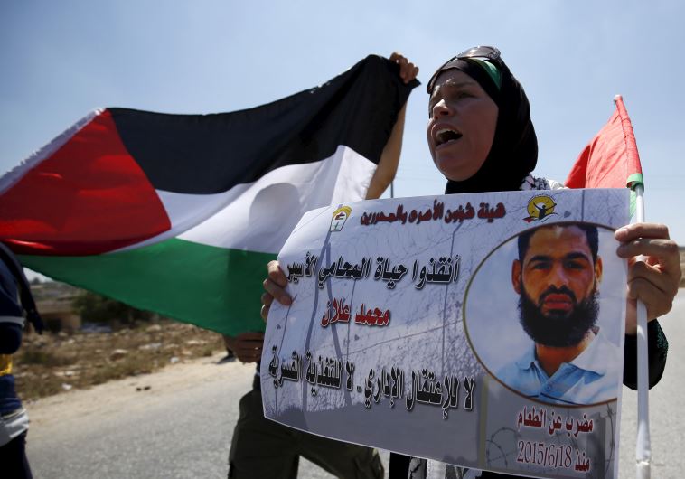 A Palestinian woman holds a picture depicting Palestinian detainee Mohammed Allan during a protest in solidarity with Allan in the West Bank village of Nabi Saleh