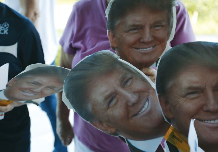 Cutouts of US Republican presidential candidate Donald Trump are held by supporters waiting in line outside a campaign town hall meeting in Derry, New Hampshire,