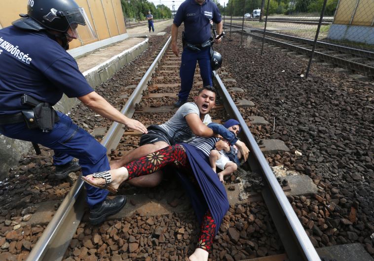 Hungarian policemen stand by the family of migrants as they wanted to run away at the railway station in the town of Bicske