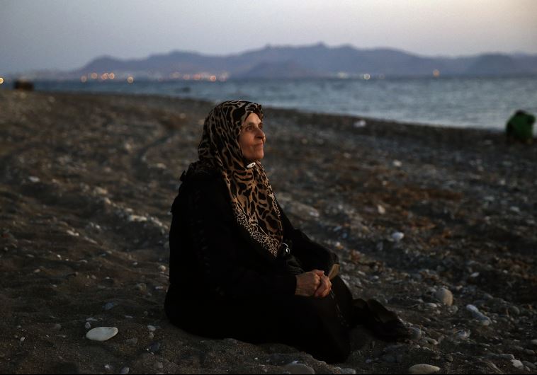 Amoun, 70, a blind Palestinian refugee who lived in the town of Aleppo in Syria, rests on a beach moments after arriving along with another forty on a dinghy in the Greek island of Kos