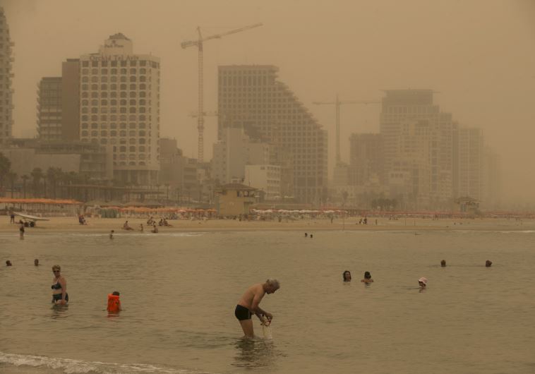 Beachgoers bath at the Mediterranean Sea during a sandstorm in Tel Aviv