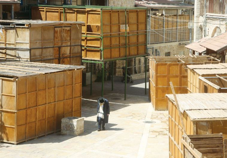 A man passes assembled succot in the ultra-Orthodox neighborhood of Mea She’arim in Jerusalem
